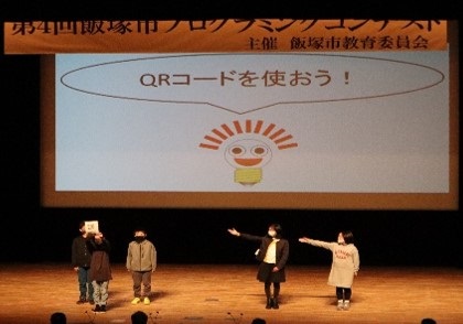 広いホールの不クリーンの前で話している写真