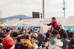 まつり関係者が福豆を投げ、来場者が手を伸ばしている様子