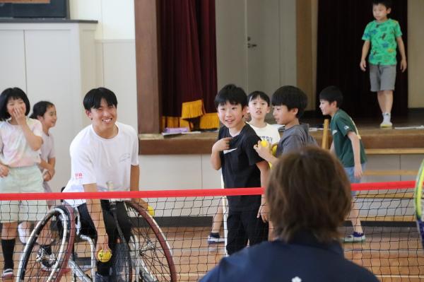体育館内でテニスの球出しを飯塚小4年の子どもたちに行う矢野選手