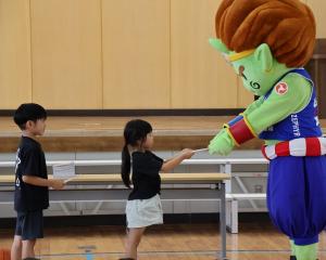 神(ジン)くんが子どもたちに自由帳を手渡している様子