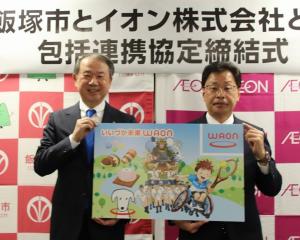 いいづか未来WAONのカードのデザインボードを持つ武井市長とイオン九州中川社長