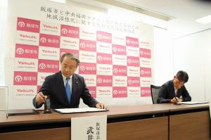 締結書にサインする武井市長と中央福岡ヤクルト販売㈱の小島社長