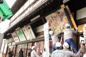 嘉穂劇場の招き絵を清掃のために動かすクラフティア社員の皆さん