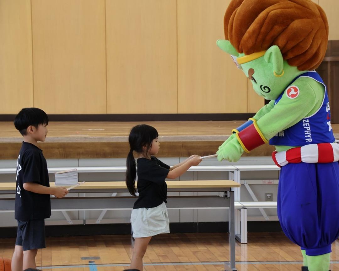 神(ジン)くんが子どもたちに自由帳を手渡している様子