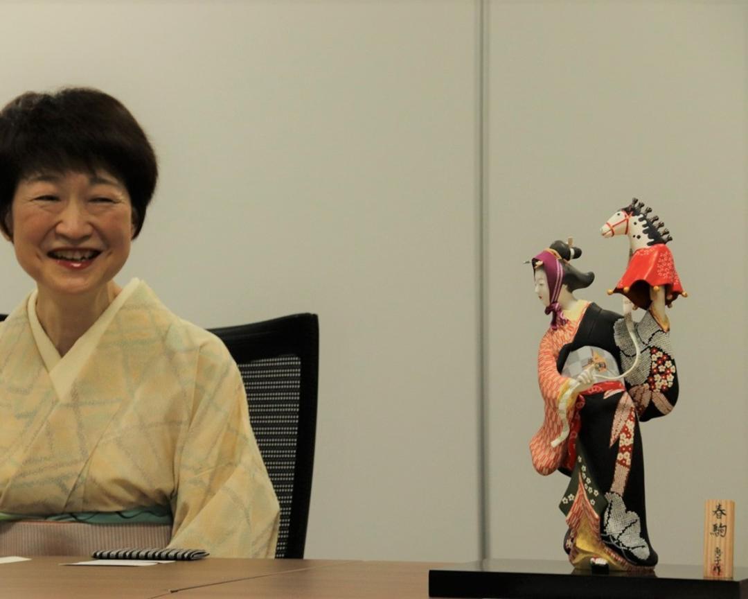 制作した人形のそばでほほ笑む緒方さん