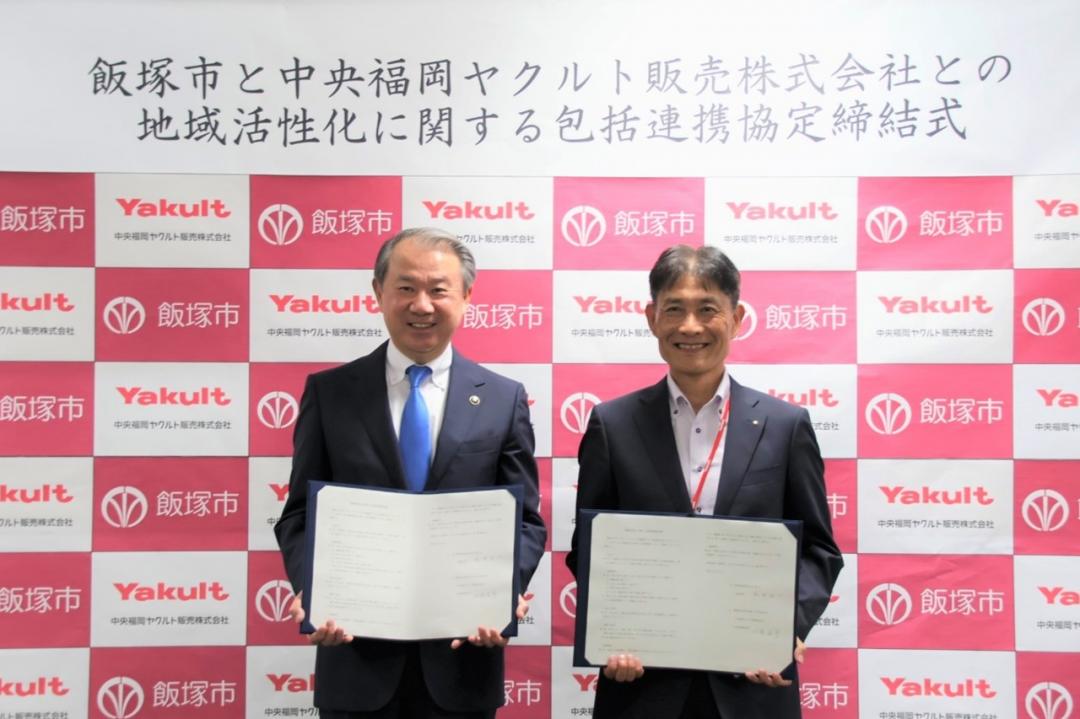 締結書を手に微笑む武井市長と中央福岡ヤクルト販売㈱の小島社長