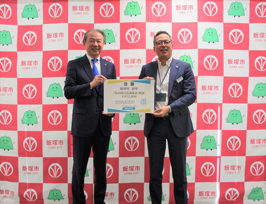 目録（パネル）を手に写真に写る武井市長と明治安田生命職員さん