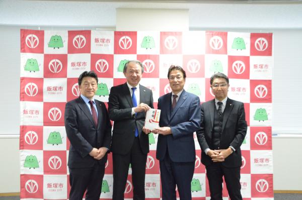 図書カードの寄贈式で正中良樹理事長から武井市長に図書カード（目録）が手渡された写真